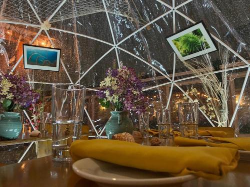 A cozy dining setup inside a transparent dome, featuring flowers, framed pictures, and elegant tableware.