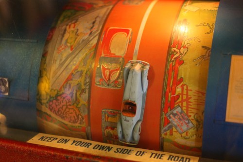 A vintage slot machine with colorful graphics and a small toy car on a spinning reel.