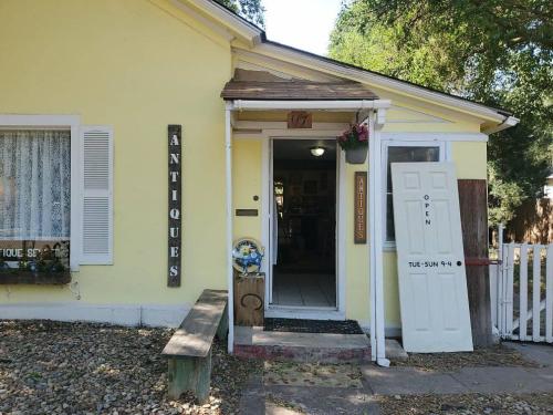 A yellow antique shop with a welcoming entrance, featuring signs and a door marked "Open" on a sunny day.