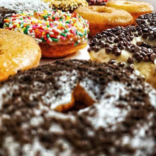 A colorful assortment of donuts topped with sprinkles, chocolate, and coconut, arranged on a plate.