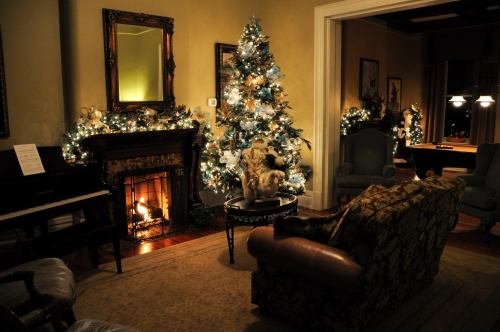 Cozy living room decorated for Christmas, featuring a tree, fireplace, and elegant furniture. Warm, festive ambiance.