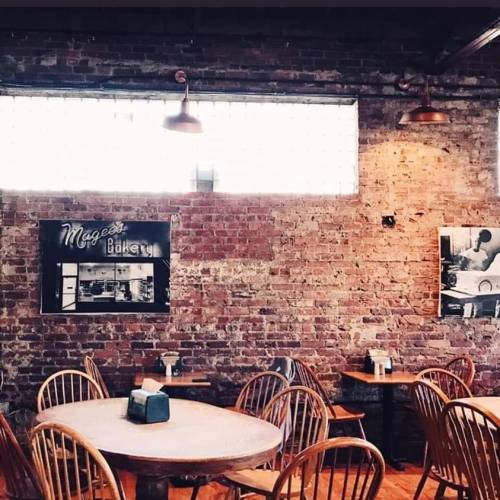 Cozy bakery interior with wooden tables, chairs, and exposed brick walls, featuring vintage bakery photos.