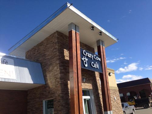 Exterior of Crazy Cow Café featuring a stone facade, wooden pillars, and a blue sky in the background.
