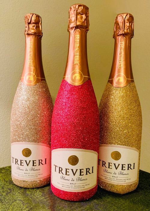 Three sparkling wine bottles with glittery gold, red, and silver finishes, labeled "Treveri Blanc de Blancs Brut."