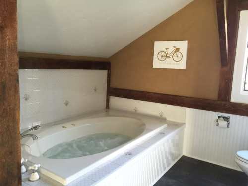 A cozy bathroom featuring a large whirlpool tub, wooden beams, and a decorative bicycle sign on the wall.