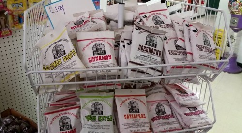 A display of assorted candy bags in a basket, featuring flavors like cinnamon, horehound, and sassafras.
