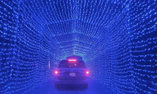 A car drives through a tunnel illuminated by vibrant blue lights, creating a mesmerizing, starry effect.