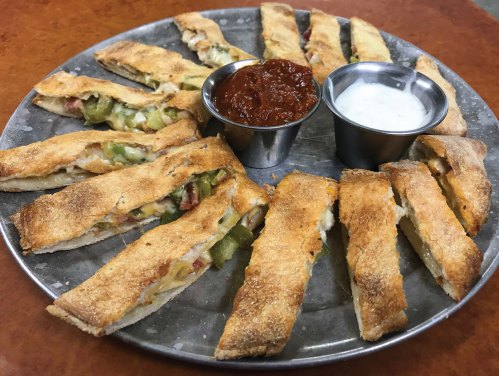 A platter of sliced, golden-brown stuffed bread with dipping sauces on the side.