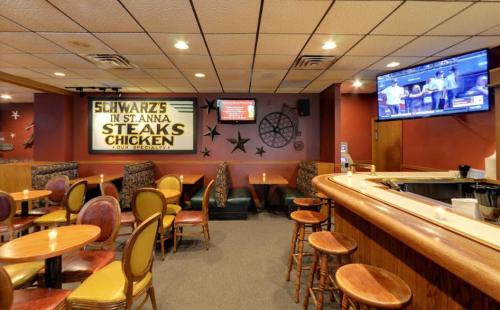 Interior of a restaurant featuring wooden tables, colorful chairs, and a TV displaying a sports event.