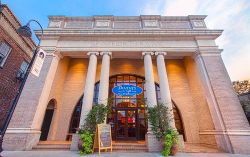 Historic building with columns, featuring a sign for "Paints on the Bay" and potted plants at the entrance.