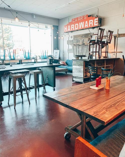 A cozy hardware store interior with wooden tables, stools, and a sign reading "Carr's Hardware."