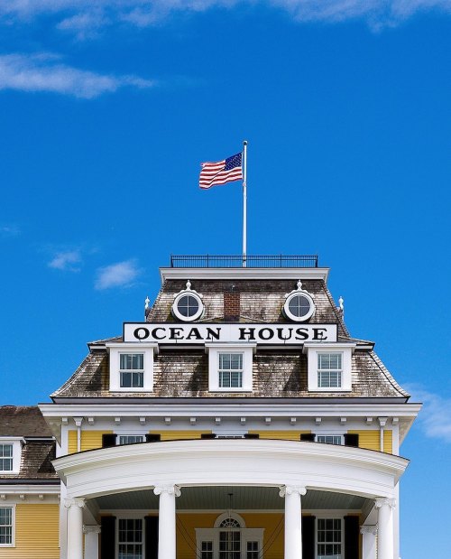 Historic Ocean House building with a flag atop, set against a clear blue sky.