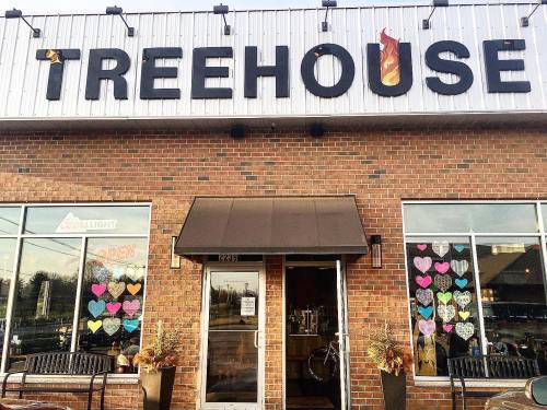 Exterior of a brick building with "Treehouse" sign, featuring heart decorations in the windows and an open sign.