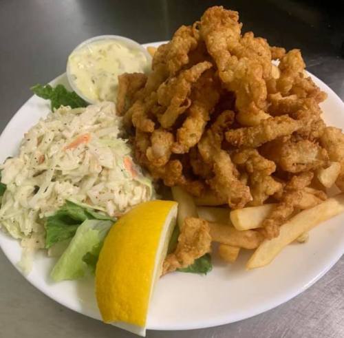 A plate of fried calamari with coleslaw, fries, a lemon wedge, and a small cup of dipping sauce.