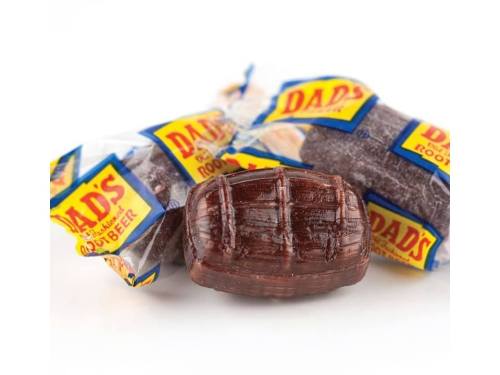 A close-up of Dad's Root Beer candies, featuring a brown, barrel-shaped candy and two wrapped pieces in the background.