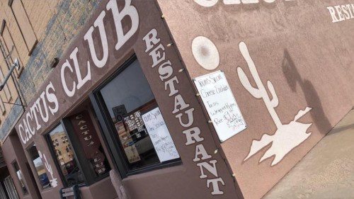 Exterior of Cactus Club Restaurant featuring a cactus mural and menu signs on a stucco wall.