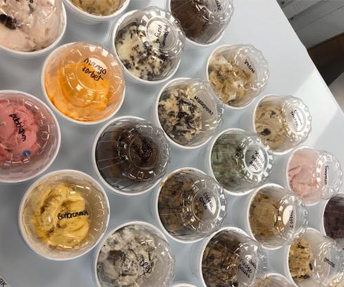 A variety of ice cream cups with different flavors labeled on top, arranged on a table.