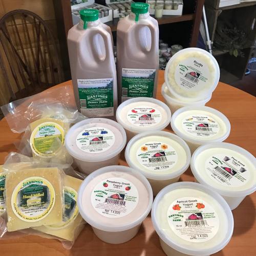 A variety of dairy products including yogurt, milk, and cheese, displayed on a wooden table.