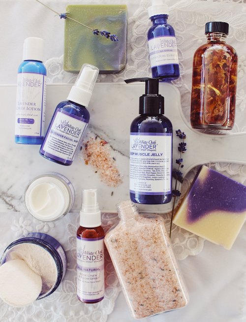 A flat lay of lavender-themed skincare products, including lotions, soaps, and bath salts, arranged on a marble surface.