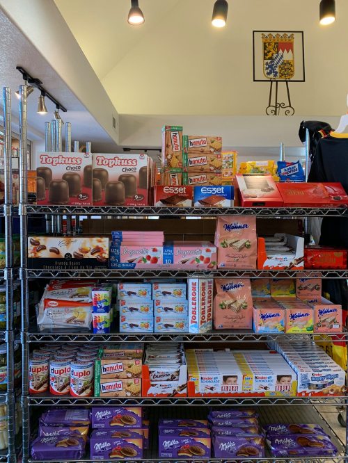 A shelf filled with various snacks and sweets, including chocolates, cookies, and packaged treats.