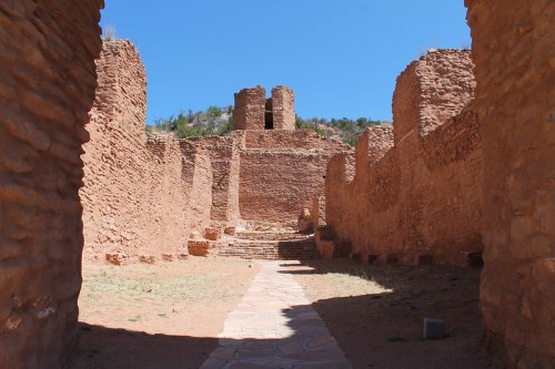 Ancient stone ruins with a pathway leading to a tower under a clear blue sky.
