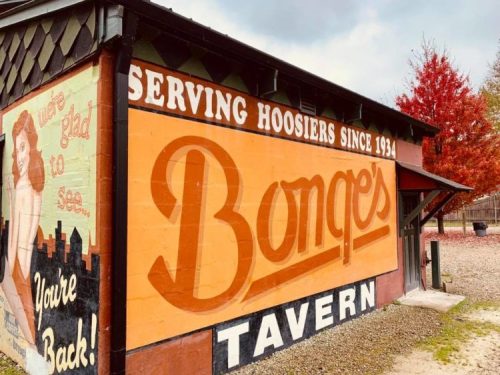 Mural on a tavern wall reading "Bongo's Tavern" with a vintage design and autumn foliage in the background.