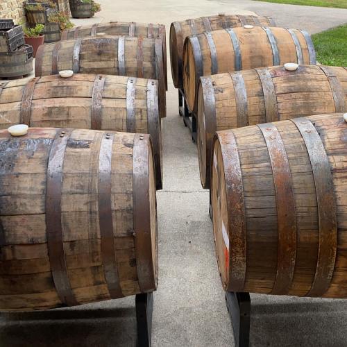 A row of wooden barrels on a concrete surface, showcasing their weathered texture and metal bands.