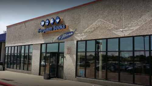 Exterior of Ferguson Books store with a sign and large windows, featuring a clear blue sky above.