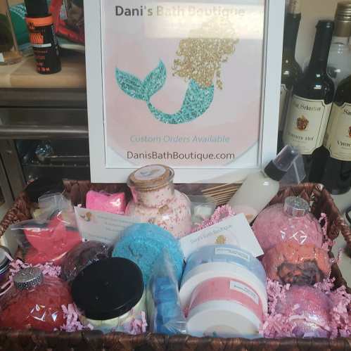 A display of bath products in a basket, featuring colorful bath bombs, scrubs, and a sign for Dani's Bath Boutique.