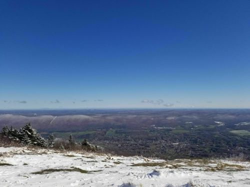 A panoramic view of a snowy landscape with rolling hills and a clear blue sky.