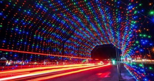 A colorful tunnel of lights with red, blue, and green hues, illuminating a night scene with car light trails.
