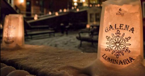 Luminaria bags with "Galena" and a snowflake design illuminate a snowy outdoor scene at night.
