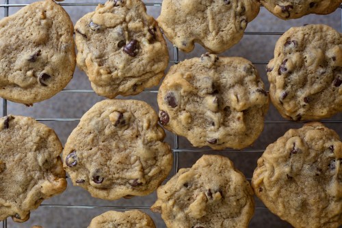 Freshly baked chocolate chip cookies cooling on a wire rack, golden brown with chocolate chunks visible.