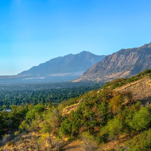 A scenic view of mountains and lush greenery under a clear blue sky.