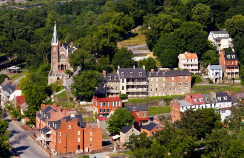 Aerial view of a historic town with a church, colorful buildings, and lush greenery surrounding the area.