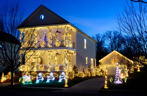 A beautifully decorated house with bright holiday lights and festive displays, set against a twilight sky.