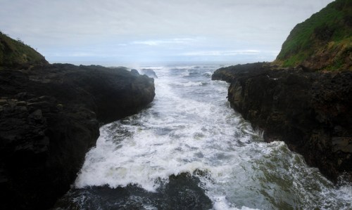 A rocky coastline with crashing waves and a cloudy sky, creating a dramatic seascape.