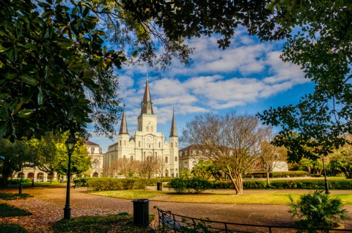 A historic building with spires surrounded by trees and a clear blue sky in a park setting.