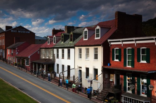 Historic buildings line a street, with a wax museum in the background and people walking along the sidewalk.