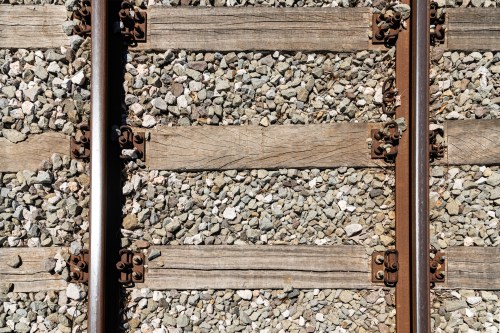 Close-up of railway tracks with wooden ties and gravel, showcasing the texture and arrangement of the materials.