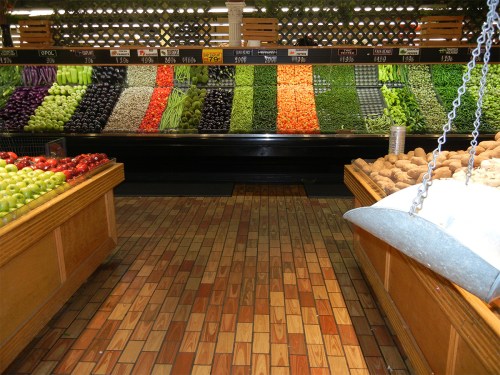 A vibrant display of fresh vegetables and fruits arranged in colorful rows in a grocery store.