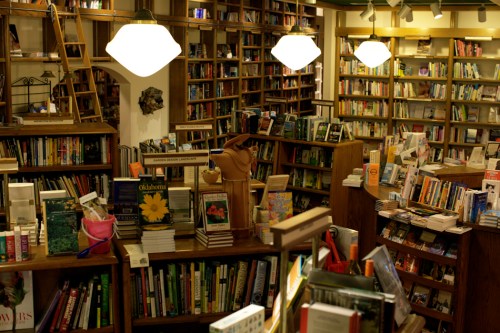 A cozy bookstore filled with wooden shelves stacked with books, warm lighting, and a welcoming atmosphere.