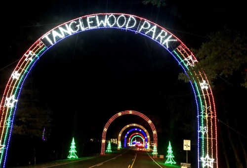 Colorful light arches welcome visitors to Tanglewood Park, lined with festive decorations and trees at night.