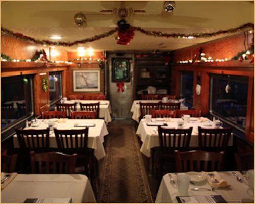 Cozy restaurant interior decorated for the holidays, featuring tables set with white linens and festive garlands.