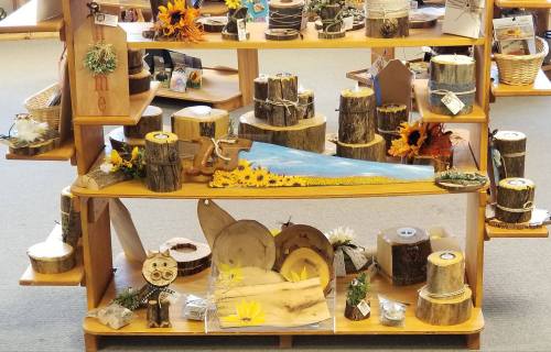 A display of handcrafted wooden items and decorations, featuring logs, flowers, and various rustic crafts.