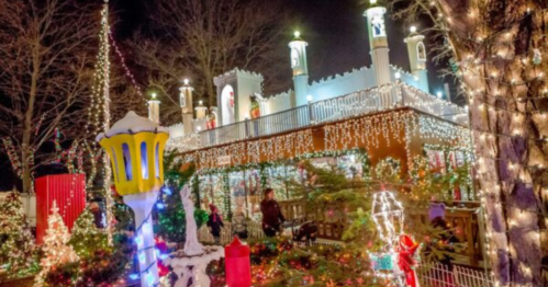 A festive scene featuring a brightly lit building surrounded by Christmas decorations and trees at night.