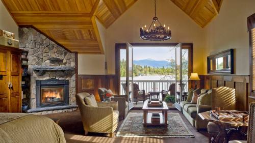 Cozy living room with a stone fireplace, large windows, and mountain views, featuring comfortable seating and warm decor.