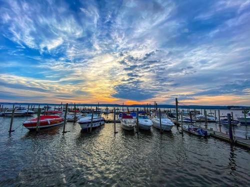 Boats docked at a marina under a colorful sunset sky with clouds reflecting on the water.