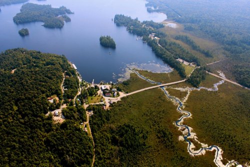 Aerial view of a serene lake surrounded by lush forests and winding waterways, with small settlements along the shore.