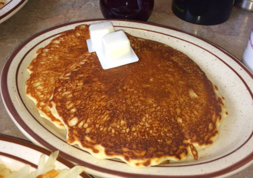 Two golden-brown pancakes on a plate, topped with two pats of butter.